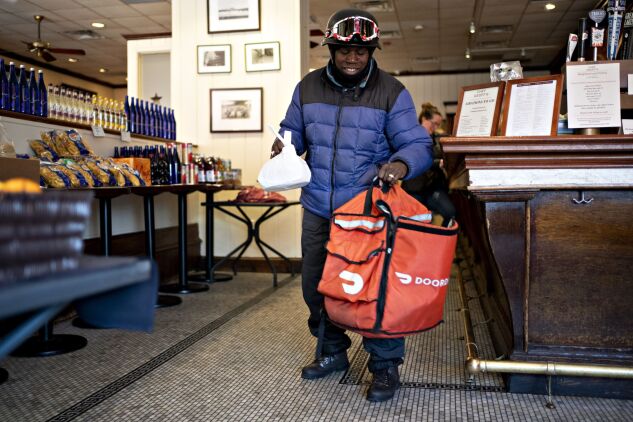A DoorDash Inc. delivery person places an order into an insulated bag at Chef Geoff's restaurant in Washington, D.C., U.S., on  March 26, 2020.