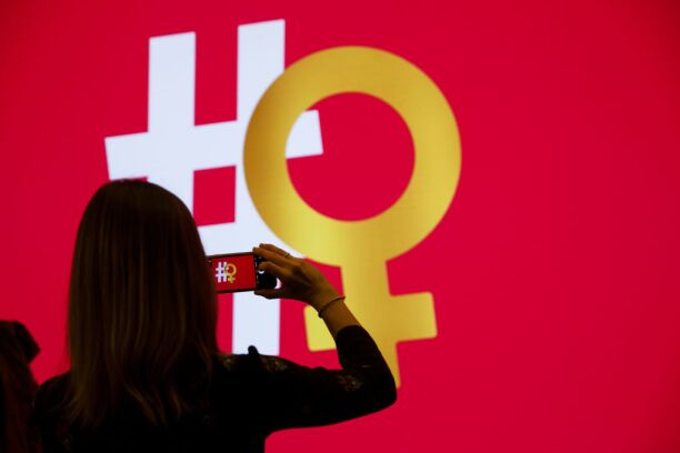 Woman takes photo of Twitter hashtag and female symbol logo.