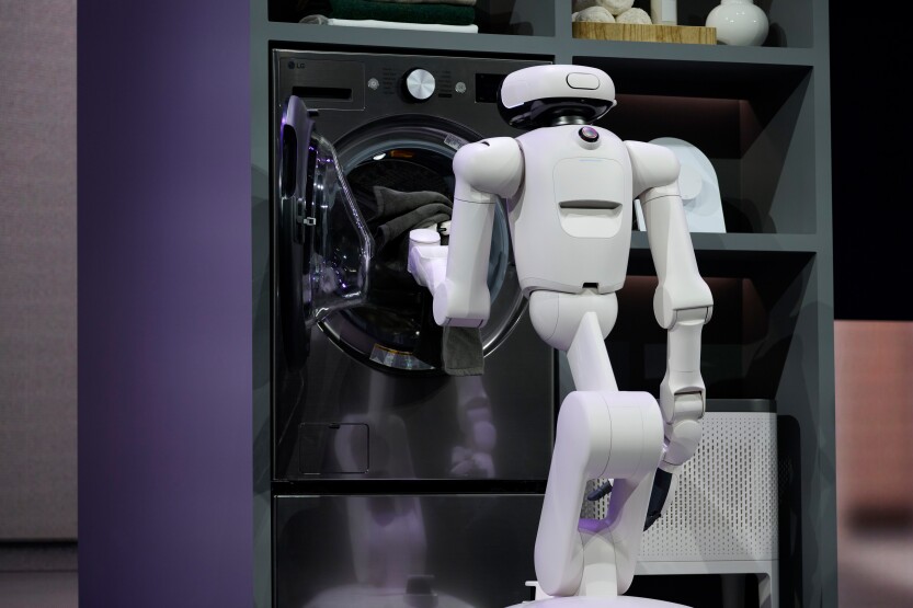 An LG Electronics CLOiD home robot puts a towel in a washing machine during the 2026 CES event in Las Vegas, Nevada, US, on Monday, Jan. 5, 2026. Photographer: Bridget Bennett/Bloomberg