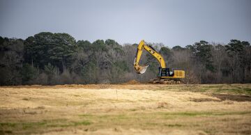 A worker operates a Caterpillar Inc. excavator at a construction site outside of Center, Tex., on Dec. 9, 2019.