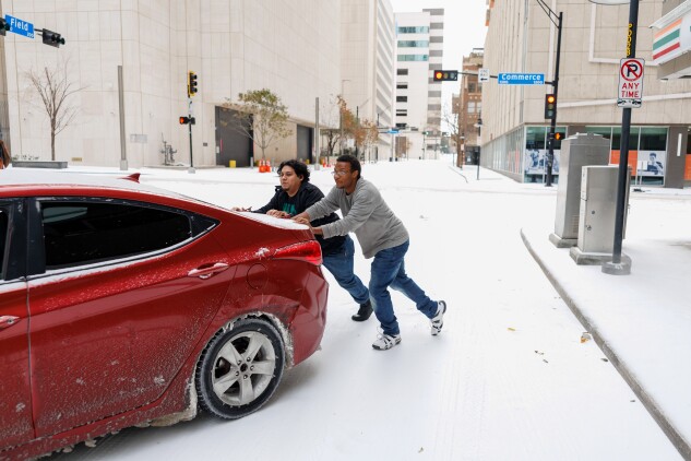 People help push a stuck vehicle during a winter storm in Dallas on Sunday