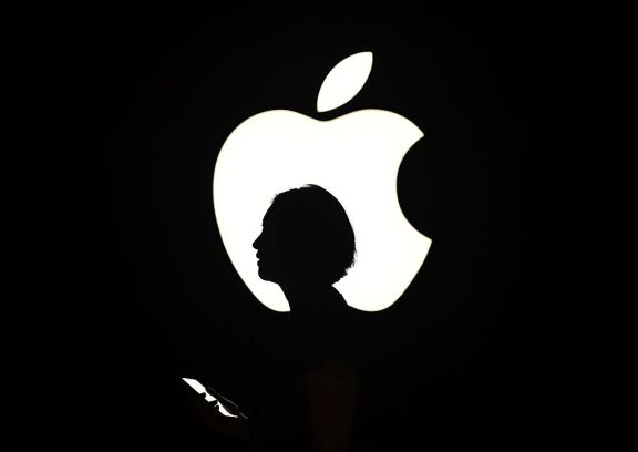 Reporter walks by the Apple logo.