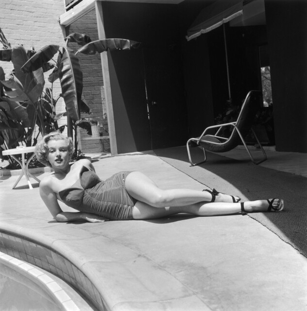 Marilyn Monroe lying on a patio next to a swimming pool deck circa 1951.