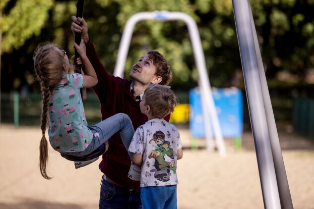 A man plays with his children in a park in Warsaw.