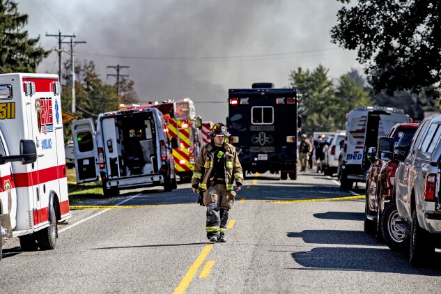 A firefighter walks down the street in Grand Blanc, Mich.